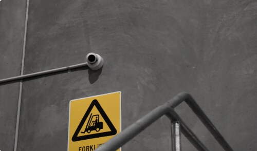 Security camera above a forklift warning sign in a warehouse