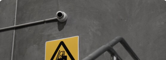 Security camera above a warehouse hazard sign